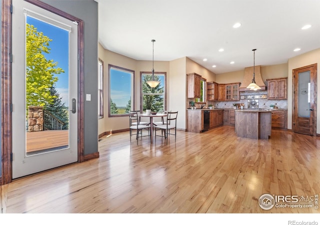 8276 Blackwood Dr, Windsor, CO 80550 - kitchen with brown cabinetry, dishwasher, custom range hood, a center island, and light wood-style flooring