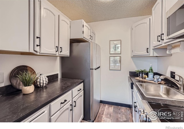3030 Oneal Pkwy # 21R, Boulder, CO 80301 - kitchen featuring dark countertops, light wood-style flooring, appliances with stainless steel finishes, a textured ceiling, and white cabinets