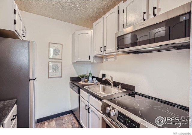 3030 Oneal Pkwy # 21R, Boulder, CO 80301 - kitchen featuring appliances with stainless steel finishes, dark countertops, light wood-style floors, a textured ceiling, and white cabinets