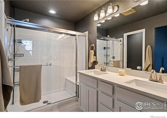 1228 104th Avenue Ct, Greeley, CO 80634 - bathroom with a stall shower, double vanity, a textured wall, and tile patterned floors