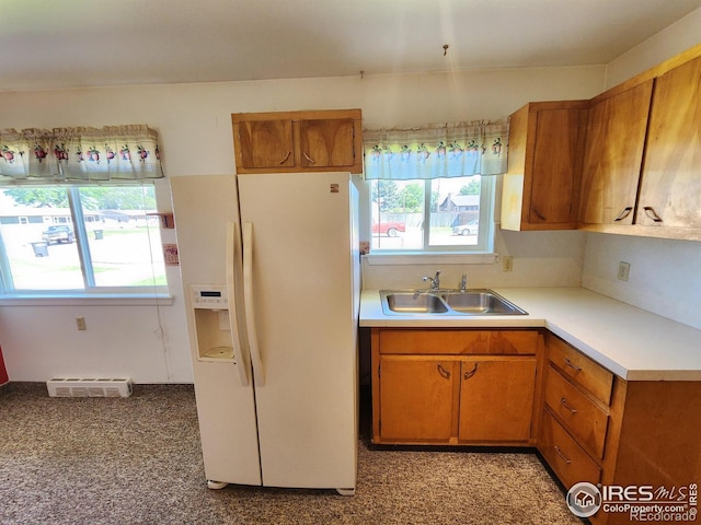 1107 Delmar St, Sterling, CO 80751 - kitchen featuring white refrigerator with ice dispenser, light countertops, and brown cabinetry