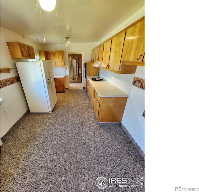 1107 Delmar St, Sterling, CO 80751 - kitchen with white refrigerator with ice dispenser, stovetop, under cabinet range hood, light countertops, and brown cabinetry