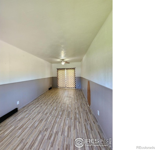 1107 Delmar St, Sterling, CO 80751 - empty room with wood finished floors, a wainscoted wall, and ceiling fan