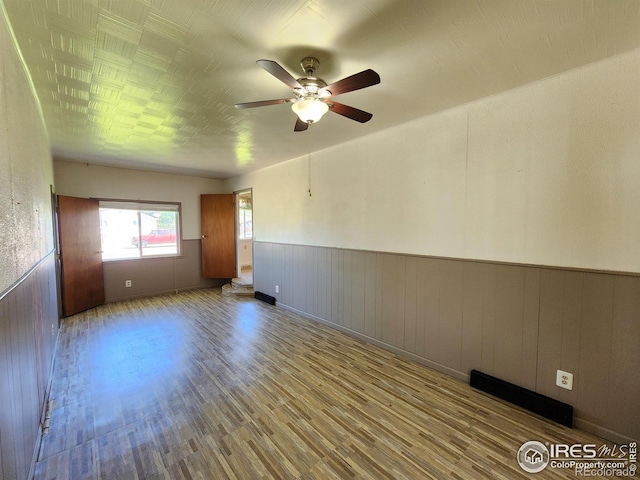 1107 Delmar St, Sterling, CO 80751 - spare room with wood finished floors, a ceiling fan, and wainscoting