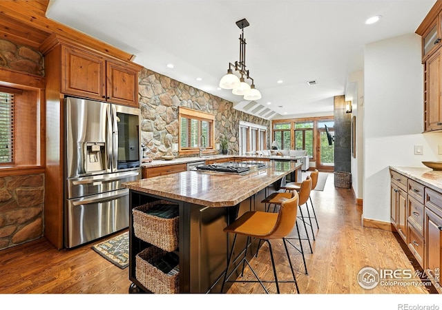 2958 6th St, Boulder, CO 80304 - kitchen featuring appliances with stainless steel finishes, light wood-type flooring, brown cabinets, a kitchen bar, and a peninsula