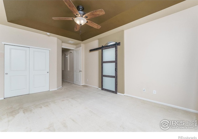 15233 W 65th Ave Unit C, Arvada, CO 80007 - unfurnished bedroom with a raised ceiling, carpet flooring, a closet, ceiling fan, and a barn door