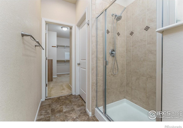 15233 W 65th Ave Unit C, Arvada, CO 80007 - full bathroom featuring a stall shower, a walk in closet, stone finish flooring, and a textured wall