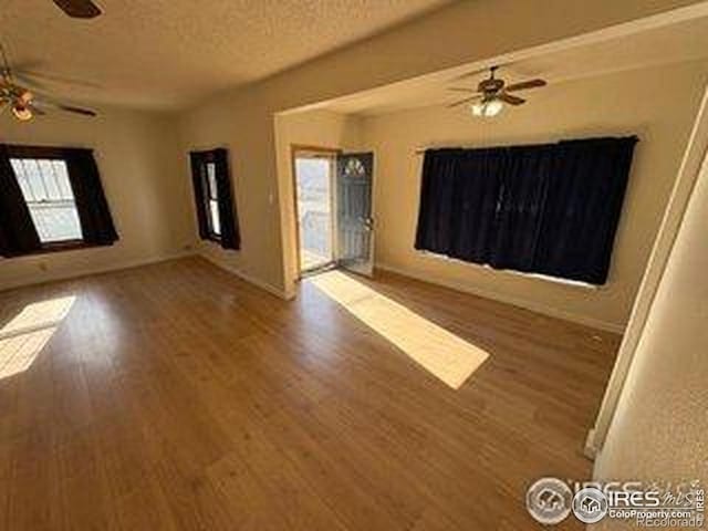 709 S 2nd Ave S, Sterling, CO 80751 - empty room featuring ceiling fan, wood finished floors, healthy amount of natural light, and a textured ceiling