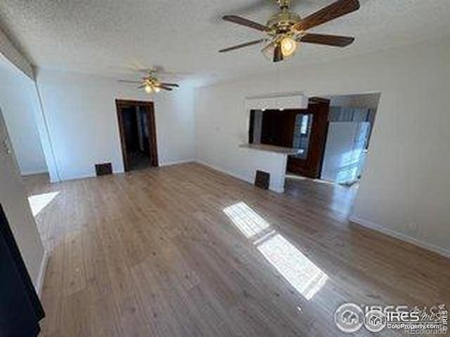 709 S 2nd Ave S, Sterling, CO 80751 - unfurnished living room with a ceiling fan, wood finished floors, and a textured ceiling