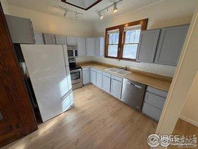 709 S 2nd Ave S, Sterling, CO 80751 - kitchen with appliances with stainless steel finishes, light wood-style flooring, gray cabinetry, rail lighting, and light countertops