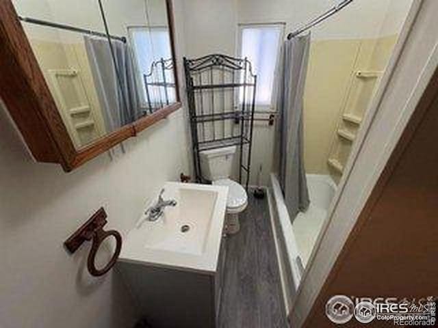 709 S 2nd Ave S, Sterling, CO 80751 - full bath featuring vanity, wood finished floors, and shower / tub combo with curtain