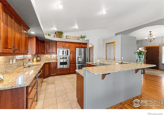 1787 Gore Creek Ct, Windsor, CO 80550 - kitchen with stainless steel appliances, a kitchen breakfast bar, lofted ceiling, backsplash, and arched walkways