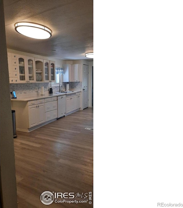 15296 County Road 39, Sterling, CO 80751 - kitchen featuring dishwasher, glass insert cabinets, tasteful backsplash, dark wood-style flooring, and light countertops