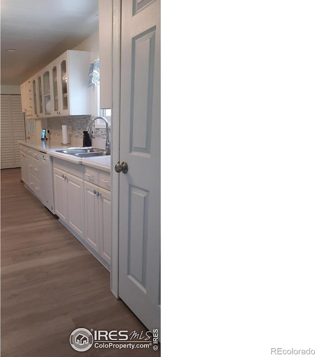 15296 County Road 39, Sterling, CO 80751 - kitchen featuring dishwasher, white cabinetry, light wood-type flooring, light countertops, and glass insert cabinets