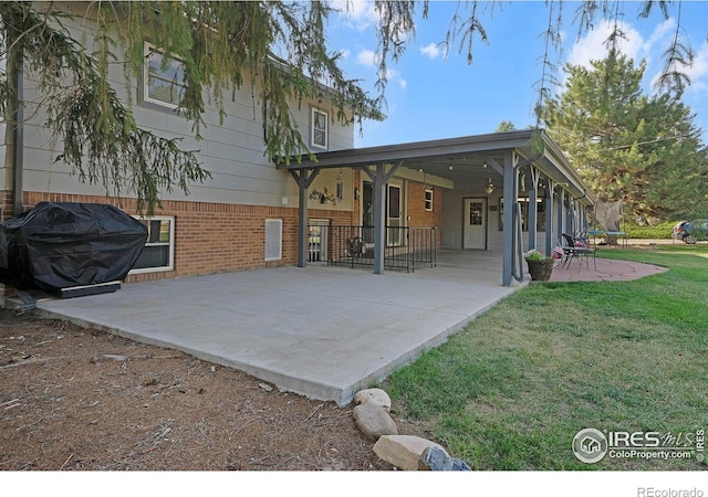 108 40th Ave, Greeley, CO 80634 - rear view of house featuring a lawn, brick siding, and a patio area