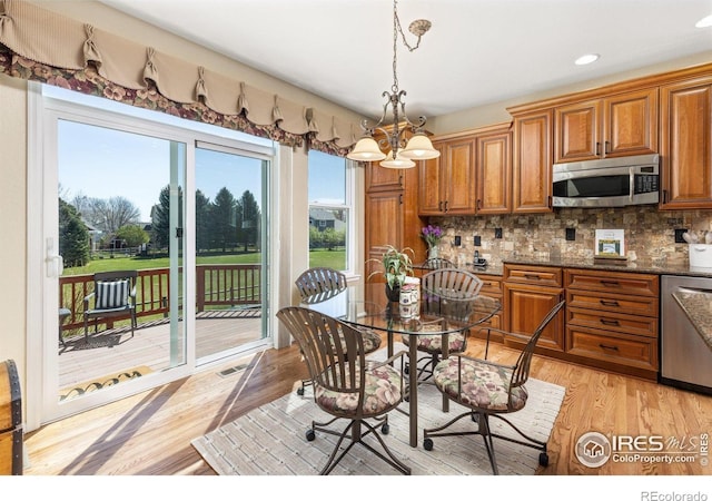 11722 Elmer Linn Dr, Longmont, CO 80504 - kitchen featuring stainless steel appliances, brown cabinetry, a chandelier, tasteful backsplash, and recessed lighting
