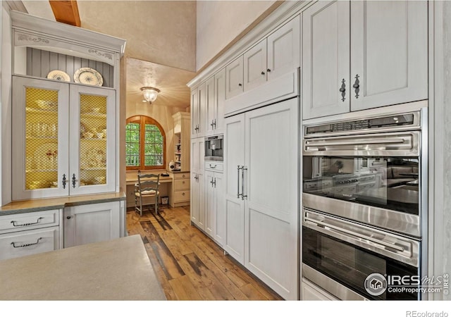 6619 Ridgeline Dr, Timnath, CO 80547 - kitchen with light wood finished floors, double oven, glass insert cabinets, and white cabinets