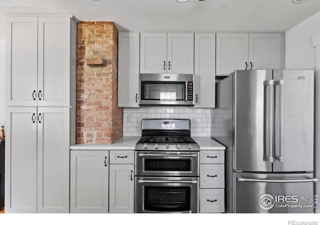 834 Emery St, Longmont, CO 80501 - kitchen with stainless steel appliances, light countertops, white cabinetry, and decorative backsplash