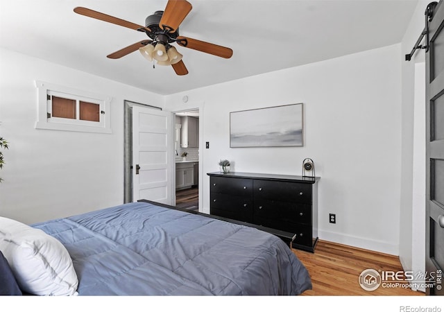 834 Emery St, Longmont, CO 80501 - bedroom with wood finished floors, a barn door, connected bathroom, and ceiling fan