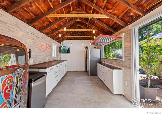 834 Emery St, Longmont, CO 80501 - kitchen with freestanding refrigerator, wooden ceiling, white cabinetry, concrete floors, and wood walls