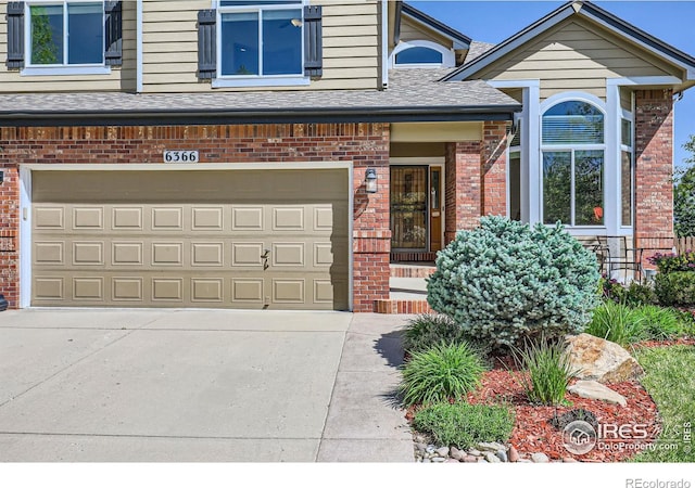 6366 Umber Cir, Arvada, CO 80403 - view of front of property featuring brick siding, an attached garage, concrete driveway, and roof with shingles