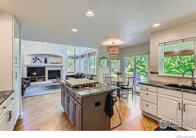 6366 Umber Cir, Arvada, CO 80403 - kitchen with white cabinetry, light wood-type flooring, dark stone countertops, healthy amount of natural light, and recessed lighting
