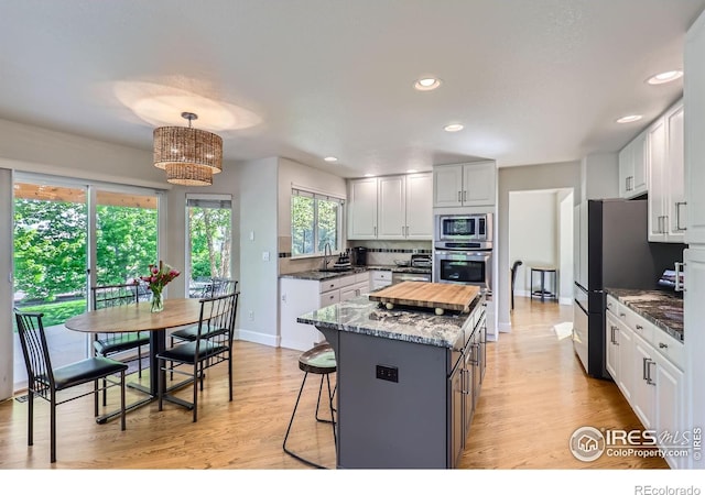 6366 Umber Cir, Arvada, CO 80403 - kitchen with appliances with stainless steel finishes, a center island, recessed lighting, a breakfast bar, and light wood-style floors