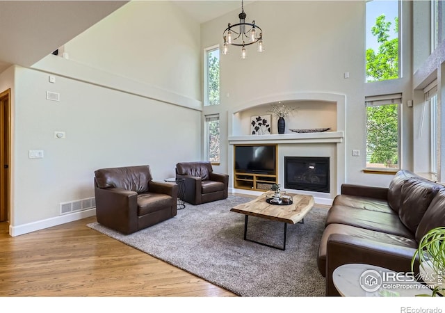 6366 Umber Cir, Arvada, CO 80403 - living room with a high ceiling, wood finished floors, a chandelier, and a glass covered fireplace