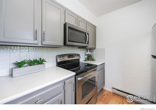 1220 Solstice Ln, Fort Collins, CO 80525 - kitchen with appliances with stainless steel finishes, gray cabinetry, light wood-style floors, and tasteful backsplash