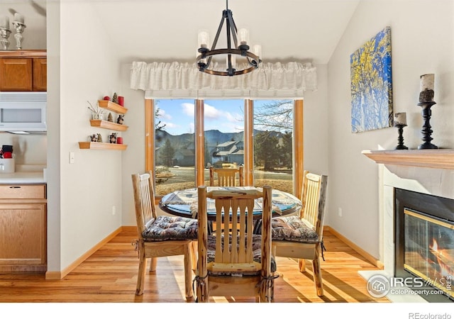 1437 Raven Cir Unit A, Estes Park, CO 80517 - dining room featuring a chandelier, light wood finished floors, a glass covered fireplace, and vaulted ceiling