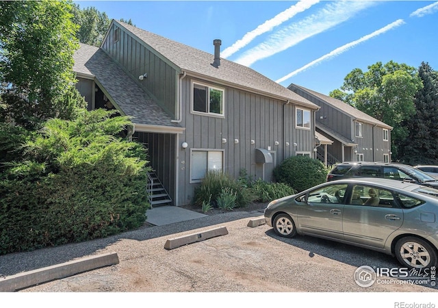 705 E Drake Rd Unit 45, Fort Collins, CO 80525 - view of home's exterior with board and batten siding, roof with shingles, stairway, and uncovered parking