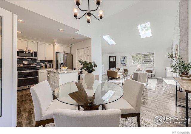 1287 Doric Dr, Lafayette, CO 80026 - dining space featuring a high ceiling, a skylight, recessed lighting, light wood-style flooring, and a chandelier