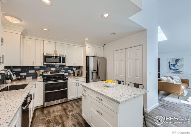 1287 Doric Dr, Lafayette, CO 80026 - kitchen featuring appliances with stainless steel finishes, white cabinetry, dark wood-type flooring, tasteful backsplash, and recessed lighting