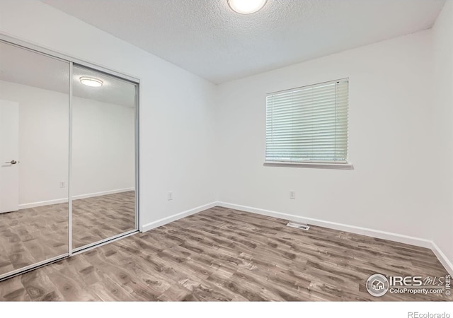 1287 Doric Dr, Lafayette, CO 80026 - unfurnished bedroom with wood finished floors, a closet, and a textured ceiling