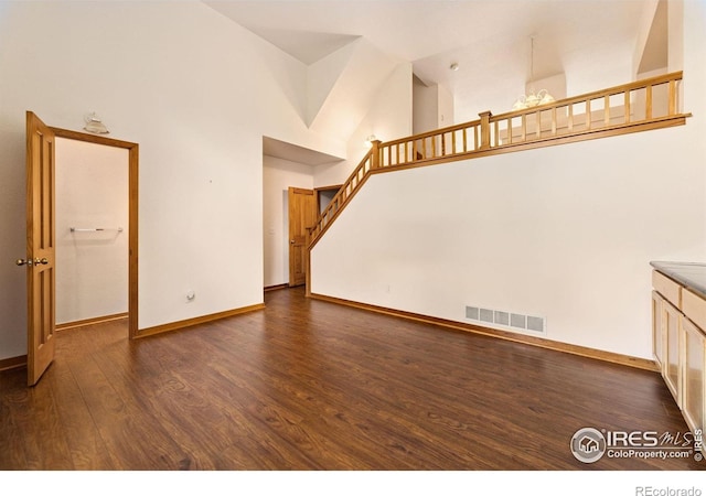3686 Oakwood Dr, Longmont, CO 80503 - unfurnished living room with high vaulted ceiling, dark wood-style flooring, and stairway