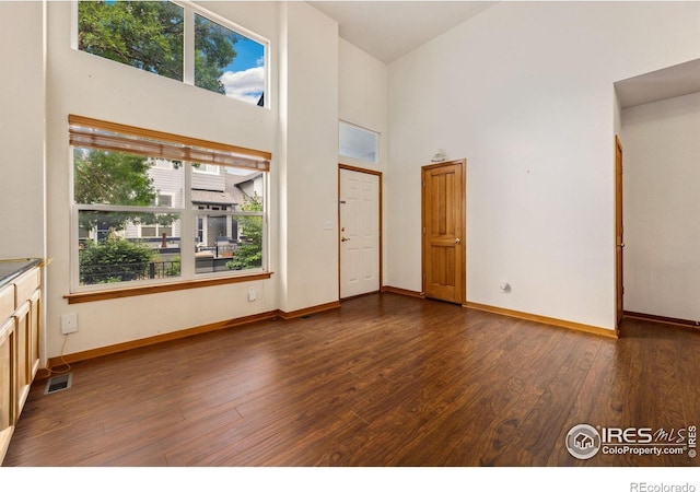 3686 Oakwood Dr, Longmont, CO 80503 - unfurnished living room featuring a towering ceiling and dark wood-type flooring