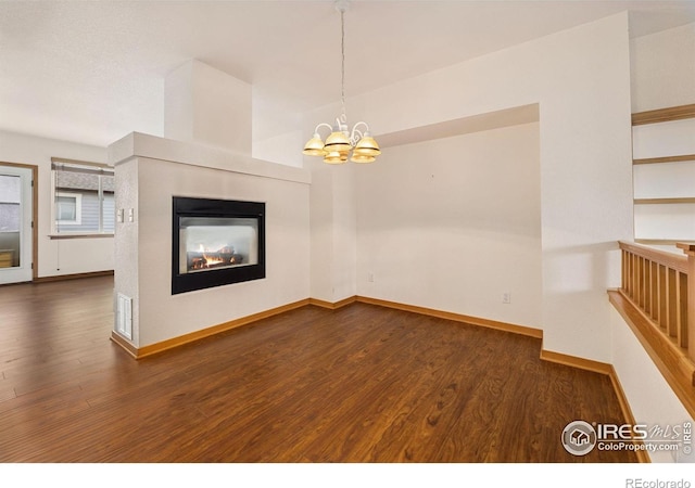 3686 Oakwood Dr, Longmont, CO 80503 - unfurnished living room featuring wood finished floors, a multi sided fireplace, and a chandelier
