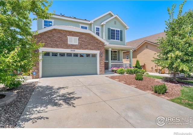 5049 S Ukraine St, Aurora, CO 80015 - view of front of home with covered porch, stone siding, a garage, and concrete driveway