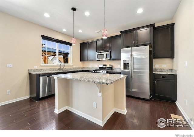 5049 S Ukraine St, Aurora, CO 80015 - kitchen with stainless steel appliances, a kitchen island, dark wood-style flooring, light stone counters, and recessed lighting
