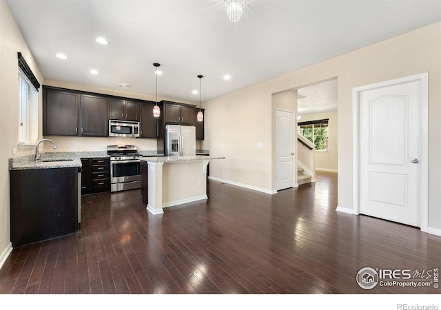 5049 S Ukraine St, Aurora, CO 80015 - kitchen featuring stainless steel appliances, a center island, dark wood-style flooring, a kitchen breakfast bar, and recessed lighting