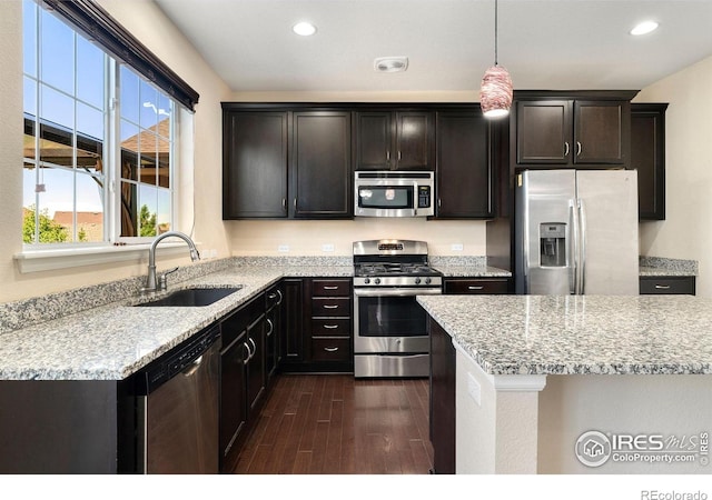 5049 S Ukraine St, Aurora, CO 80015 - kitchen with stainless steel appliances, dark wood-style floors, recessed lighting, hanging light fixtures, and light stone counters