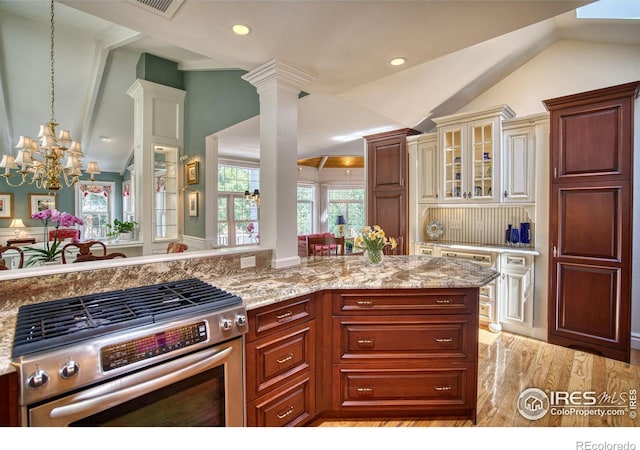 4471 Wellington Rd, Boulder, CO 80301 - kitchen featuring stainless steel range with gas cooktop, vaulted ceiling, a chandelier, light stone counters, and glass insert cabinets