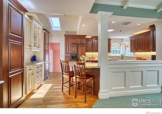 4471 Wellington Rd, Boulder, CO 80301 - kitchen with light wood-style floors, a skylight, tasteful backsplash, light stone countertops, and glass insert cabinets