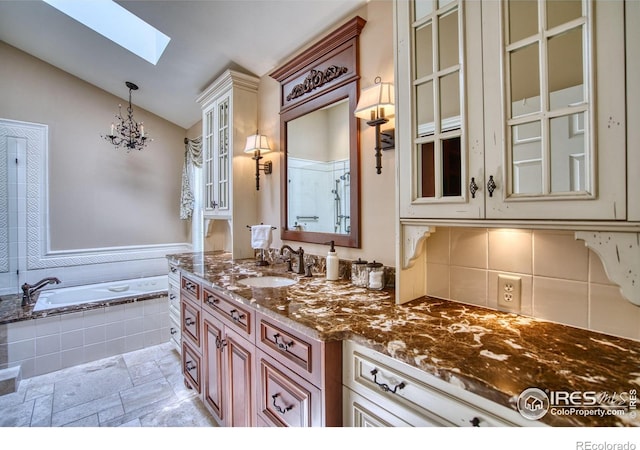 4471 Wellington Rd, Boulder, CO 80301 - full bath featuring a skylight, vaulted ceiling, vanity, a bath, and tasteful backsplash