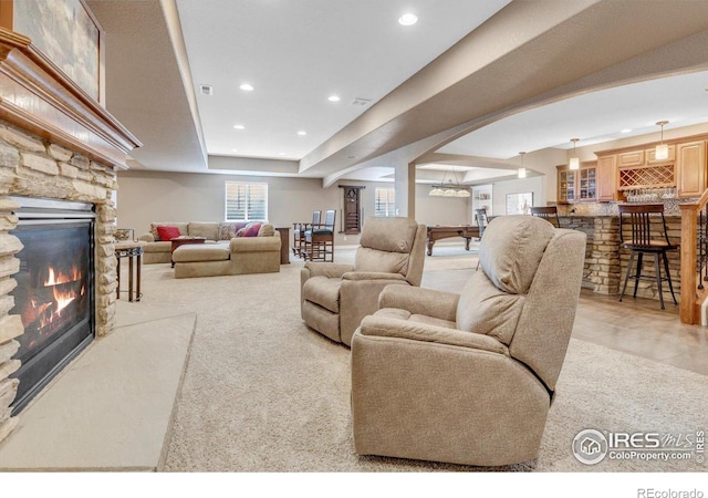 15002 Cosmos Way, Broomfield, CO 80023 - living room featuring recessed lighting, arched walkways, a stone fireplace, ornate columns, and a tray ceiling