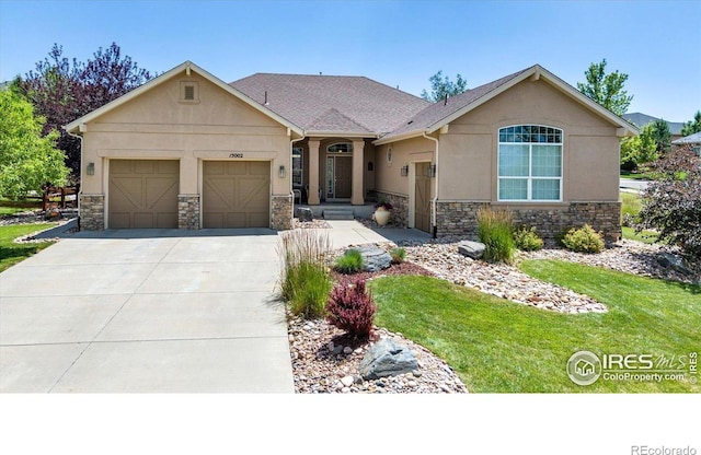 15002 Cosmos Way, Broomfield, CO 80023 - view of front of home with stone siding, driveway, stucco siding, an attached garage, and a front yard
