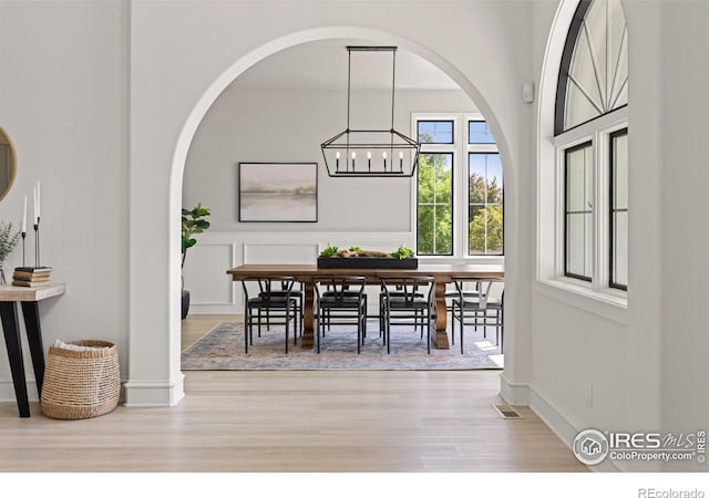 16636 Krameria Way, Brighton, CO 80602 - dining space featuring wood finished floors, a chandelier, and arched walkways