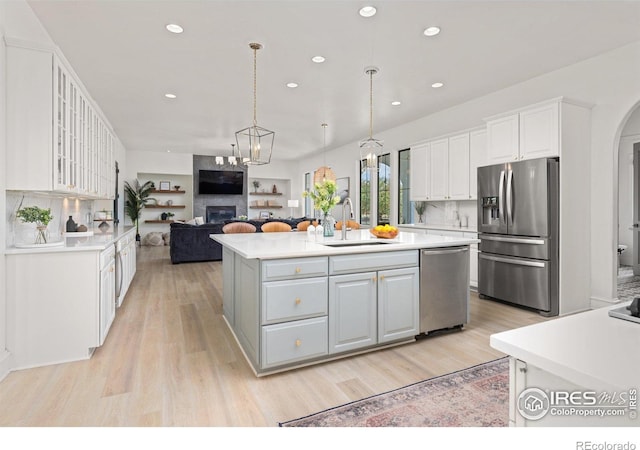 16636 Krameria Way, Brighton, CO 80602 - kitchen featuring stainless steel appliances, a fireplace, white cabinetry, light wood finished floors, and recessed lighting