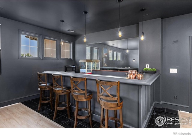 16636 Krameria Way, Brighton, CO 80602 - indoor wet bar featuring tile patterned floors, stainless steel microwave, and hanging light fixtures
