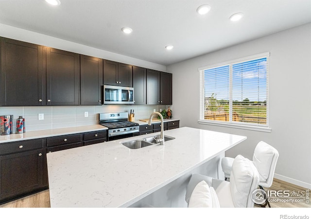 5766 Ranch St, Longmont, CO 80504 - kitchen featuring appliances with stainless steel finishes, light wood-style floors, recessed lighting, decorative backsplash, and a breakfast bar
